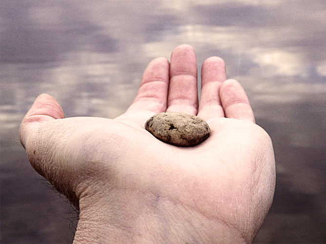 (Photo: a hand holding a pebble)
